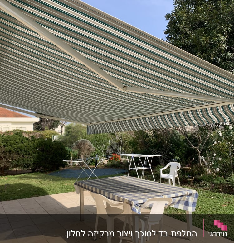 סוכך פסים ירוק לבן מעל שולחן בגינה